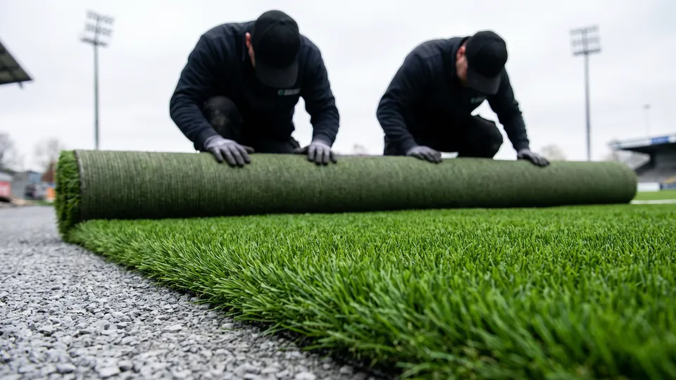 Бригада GrassPro раскатывает рулон искусственной травы